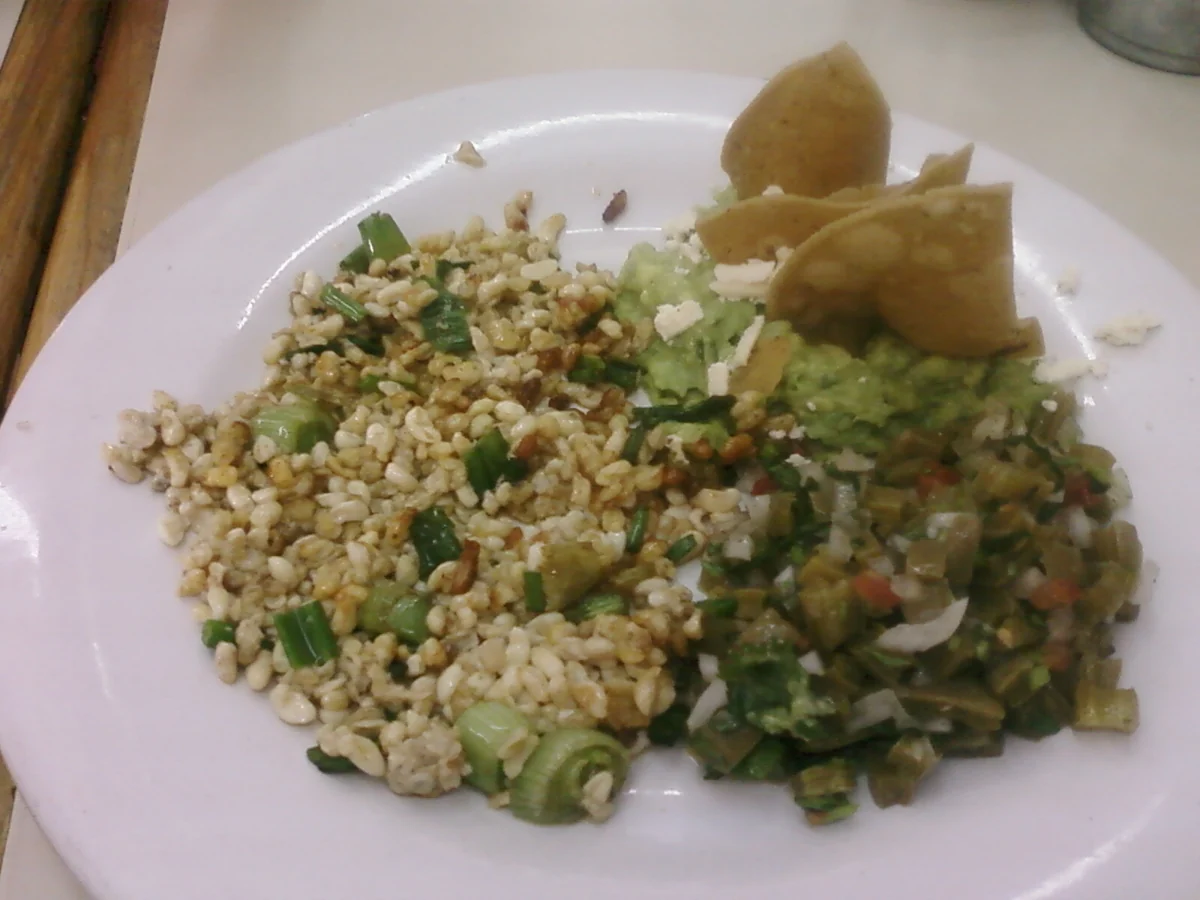 Escamoles on the left of a plate with nopales, avocado and tortilla.